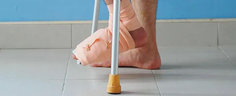 An injured man walking on crutches with his foot and ankle wrapped from an accident in Jacksonville.